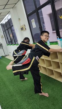 2 Kids balancing equipment on their legs while kickboxing - learning through play